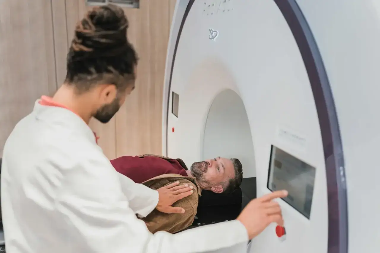 Lekarz przygotowuje pacjenta do zabiegu, wyjaśniając, na czym polega radioterapia. Pacjent leży na stole terapeutycznym w nowoczesnym aparacie.