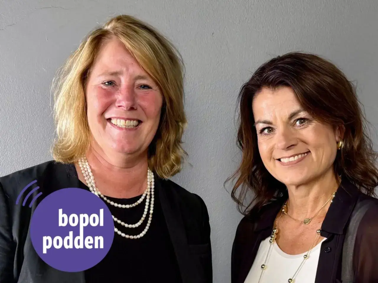 Två leende kvinnor, en med blont hår och pärlhalsband, den andra med brunt hår och guldsmycken. Johanna Frelin är en av dem.