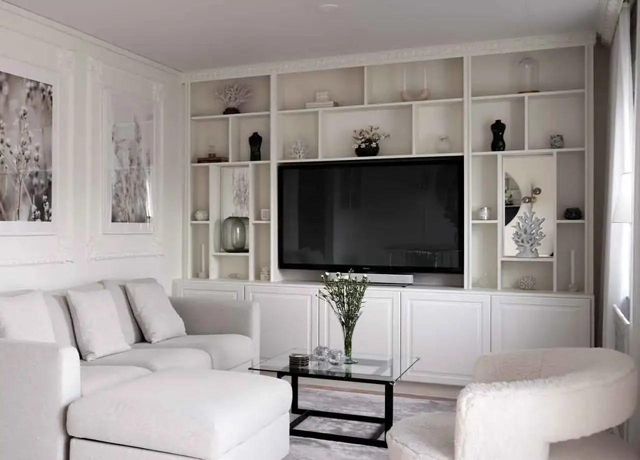 En vit, stilren bokhylla med TV i mitten ger inspiration f&ouml;r ett modernt vardagsrum. Mjuk soffa och detaljer i inredningen skapar en inbjudande atmosf&auml;r.