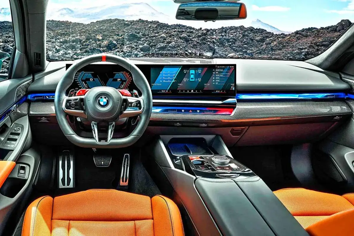Wnętrze BMW M5 CS z pomarańczową tapicerką i nowoczesnym panelem cyfrowym.