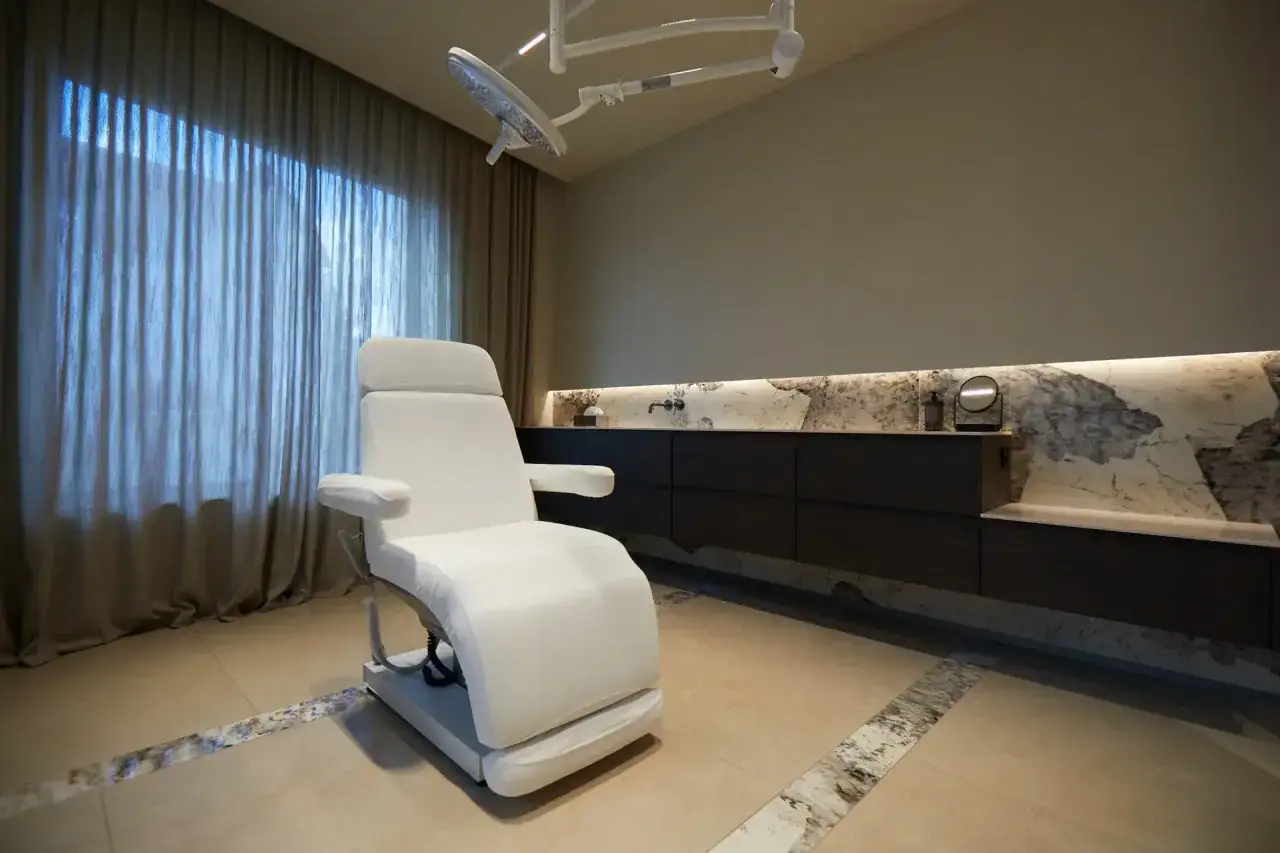 Nowoczesny gabinet dermatologii estetycznej z fotelem zabiegowym i lampą.
