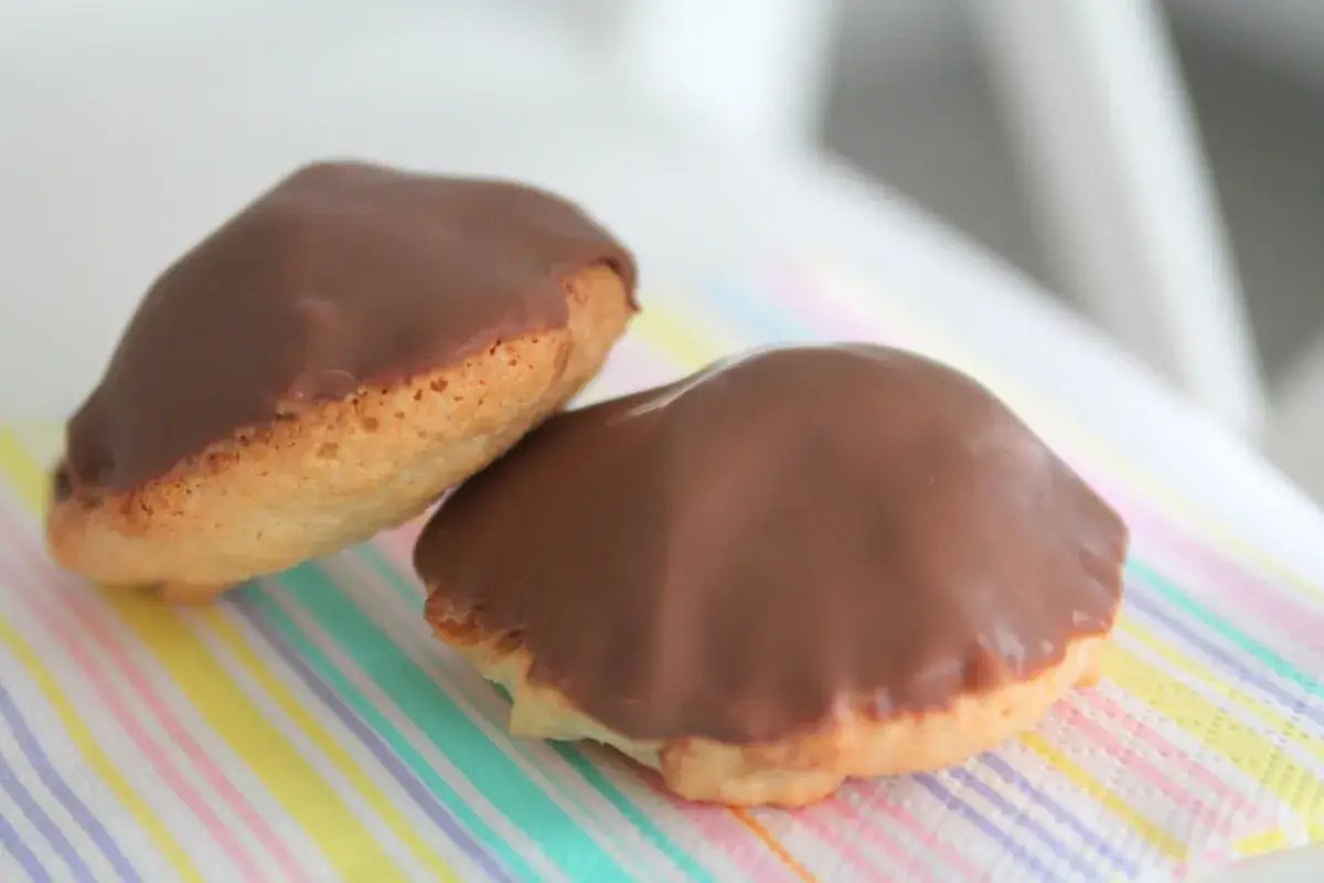 Två chokladöverdragna biskvier på en randig servett. Perfekt för ett enkelt biskvier recept.