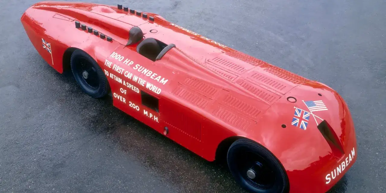 Czerwony, opływowy Sunbeam 1000 HP, najszybsze auto na świecie, z flagami USA i Wielkiej Brytanii.
