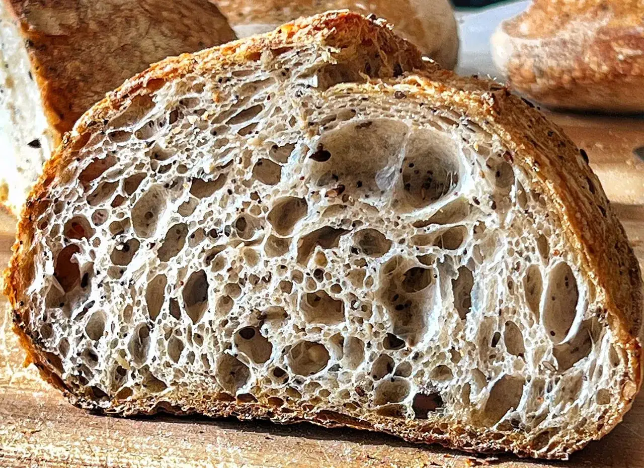 Fetta di pane con lievito madre, alveolatura perfetta e crosta dorata. Un capolavoro artigianale.