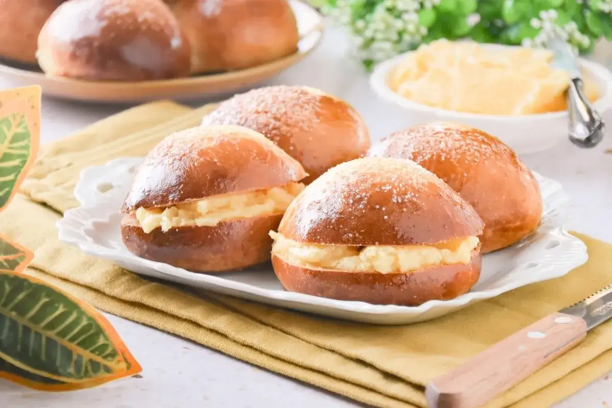 Deliciosos bollos de mantequilla rellenos de crema, espolvoreados con azúcar. Un placer para el paladar.