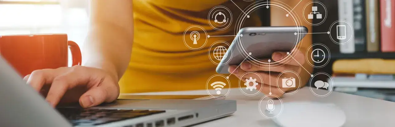 Persona interactuando con un smartphone y port&aacute;til, rodeada de iconos de conectividad y datos. Ideal para un curso de anal&iacute;tica digital.