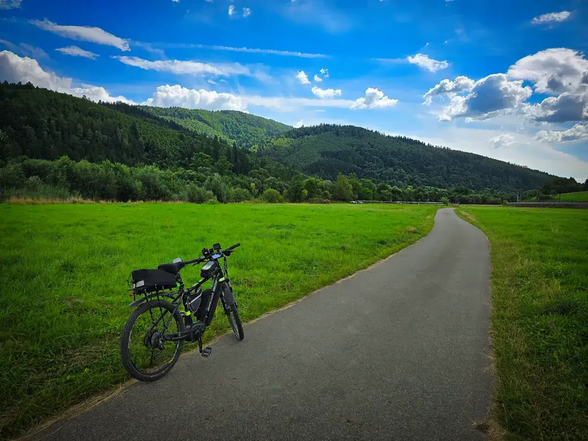 Rower elektryczny czeka na przygodę na trasie rowerowej Velo Soła. Zielone łąki i zalesione wzgórza zapraszają do odkrywania piękna natury.