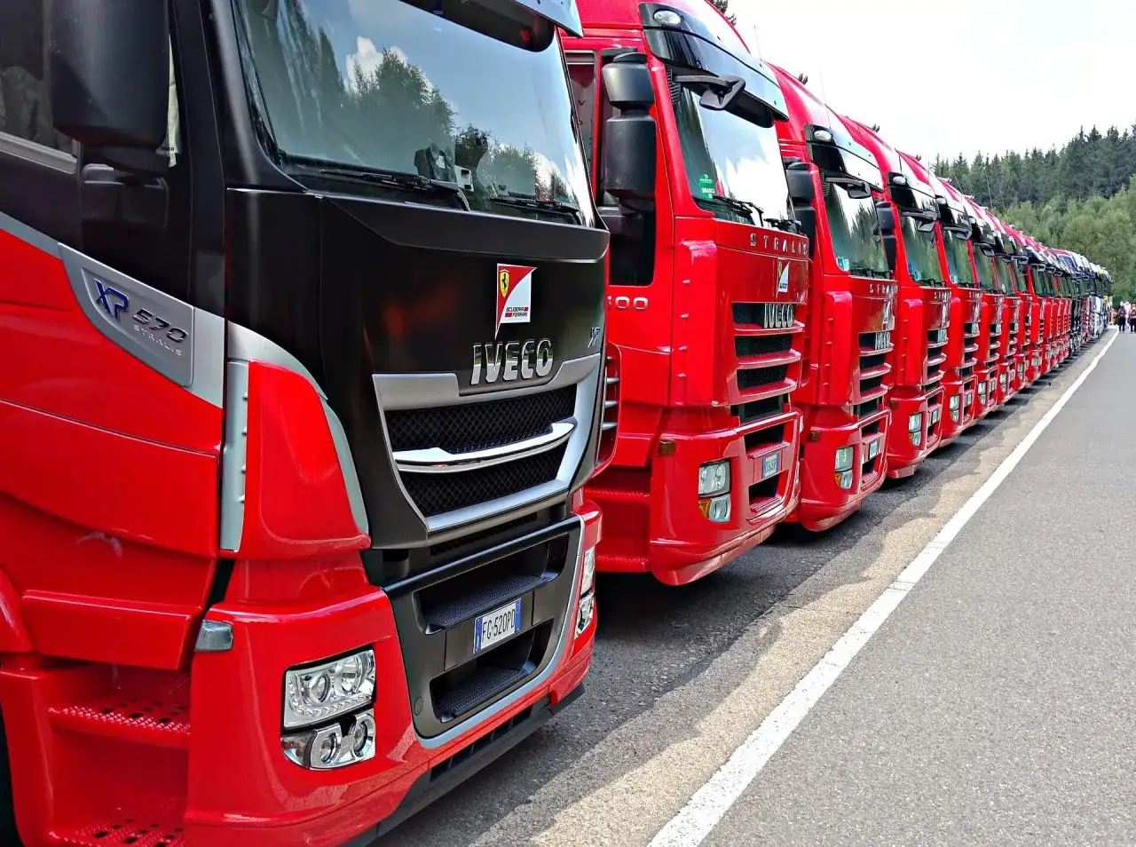 Rząd czerwonych Iveco Stralis gotowych do szybkiej spedycji. Lśniące ciężarówki czekają na trasę.