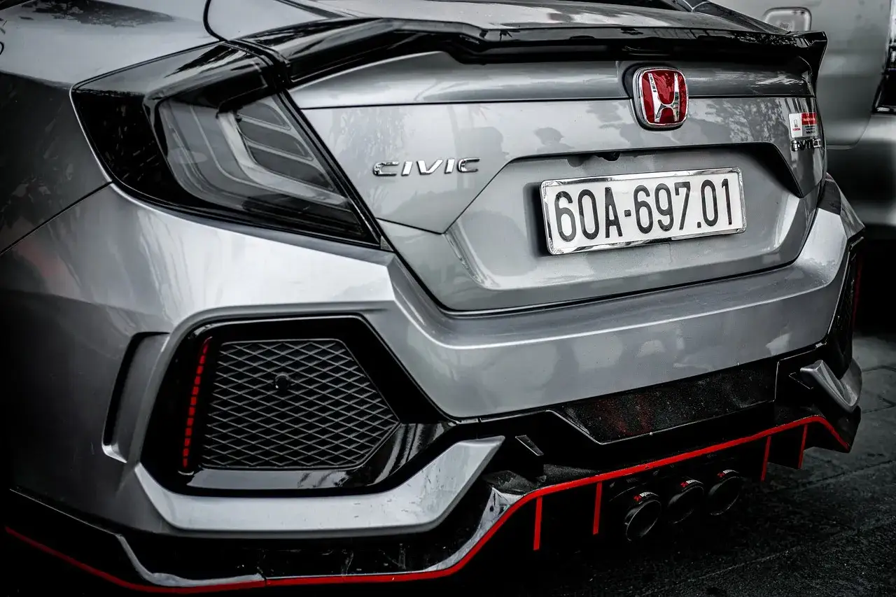 Tył sportowego japońskiego samochodu Honda Civic z potrójnym wydechem i czerwonymi akcentami.