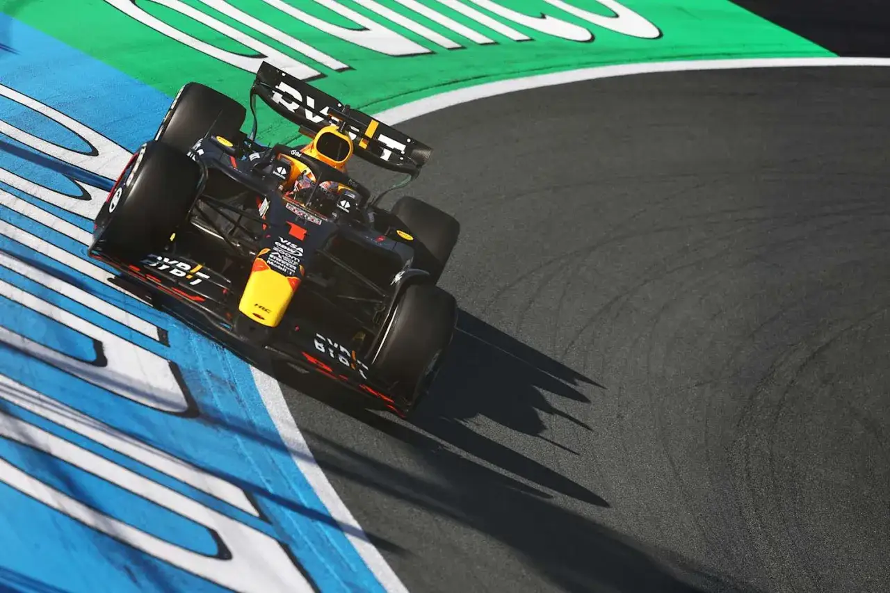 Un coche de **Grand Prix F1** negro y amarillo toma una curva cerrada, dejando marcas de neum&aacute;ticos en el asfalto.
