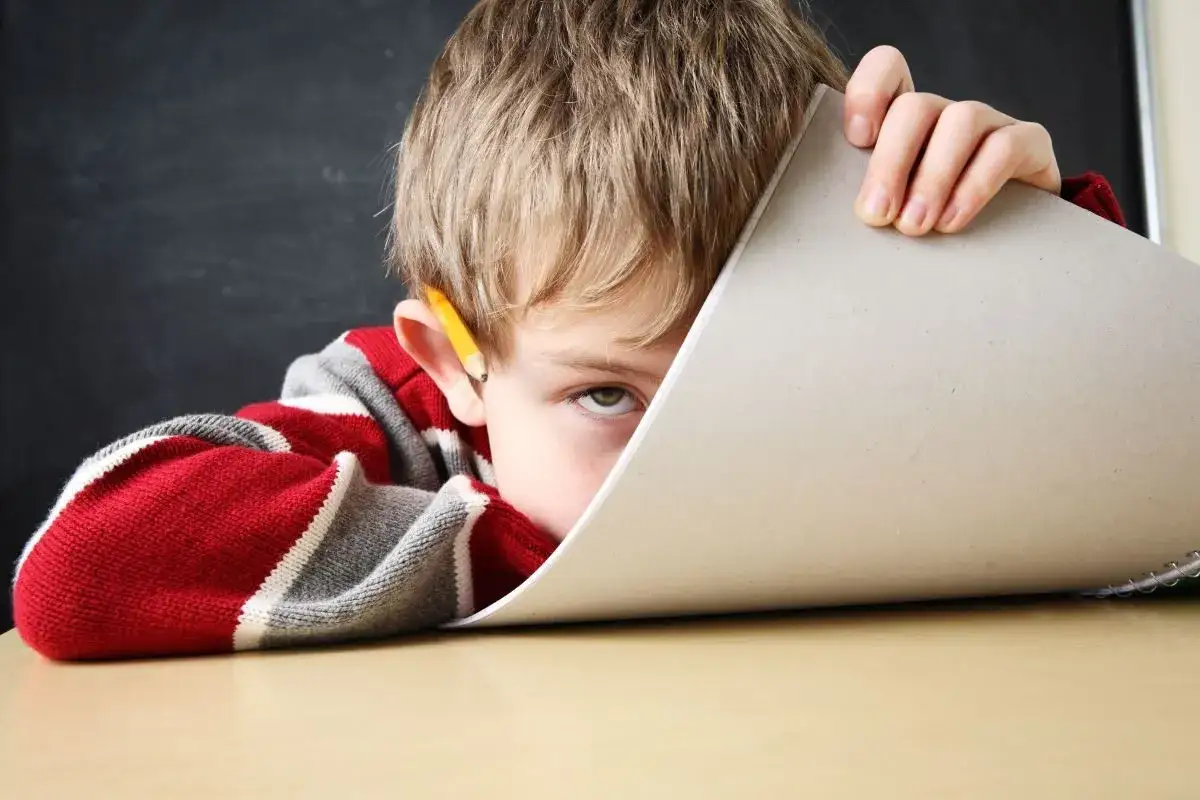 Chłopiec z ołówkiem za uchem, ukrywający się za kartką. Czy to objawy ADHD u 2 latka?