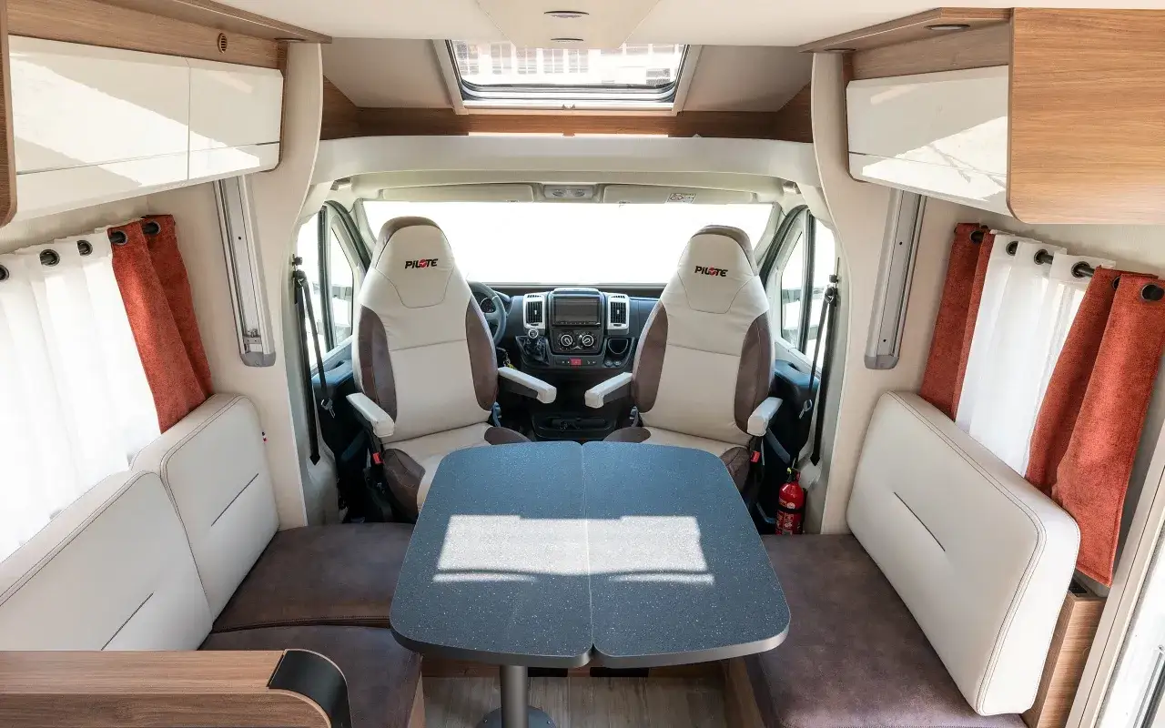 Int&eacute;rieur d'un camping-car Pilote P 726 FC. Avis sur ce mod&egrave;le : si&egrave;ges confortables, table modulable, ambiance cosy.
