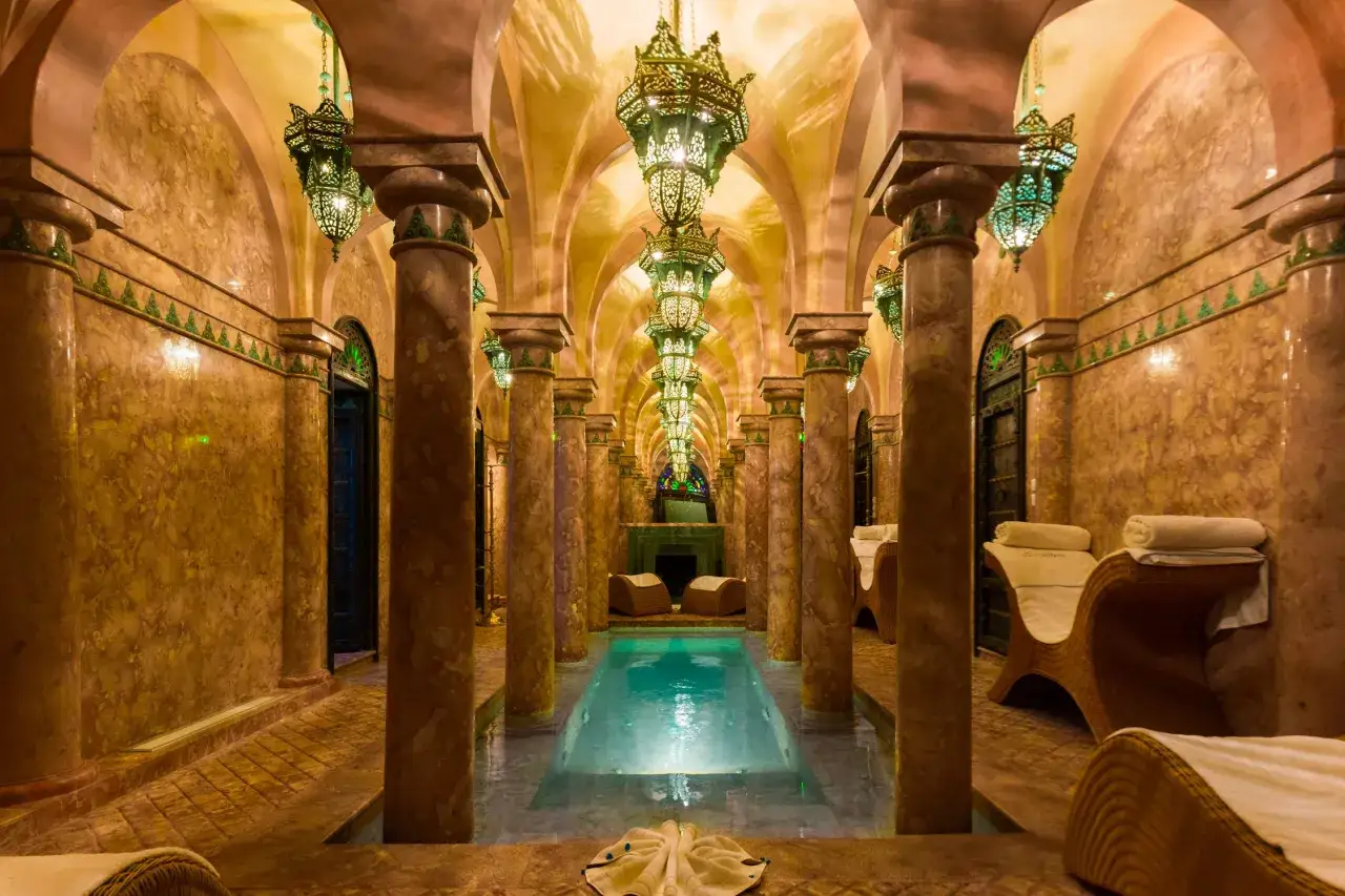 En lyxig hammam i Marrakech med en pool, vackra lampor och avkopplande solstolar.
