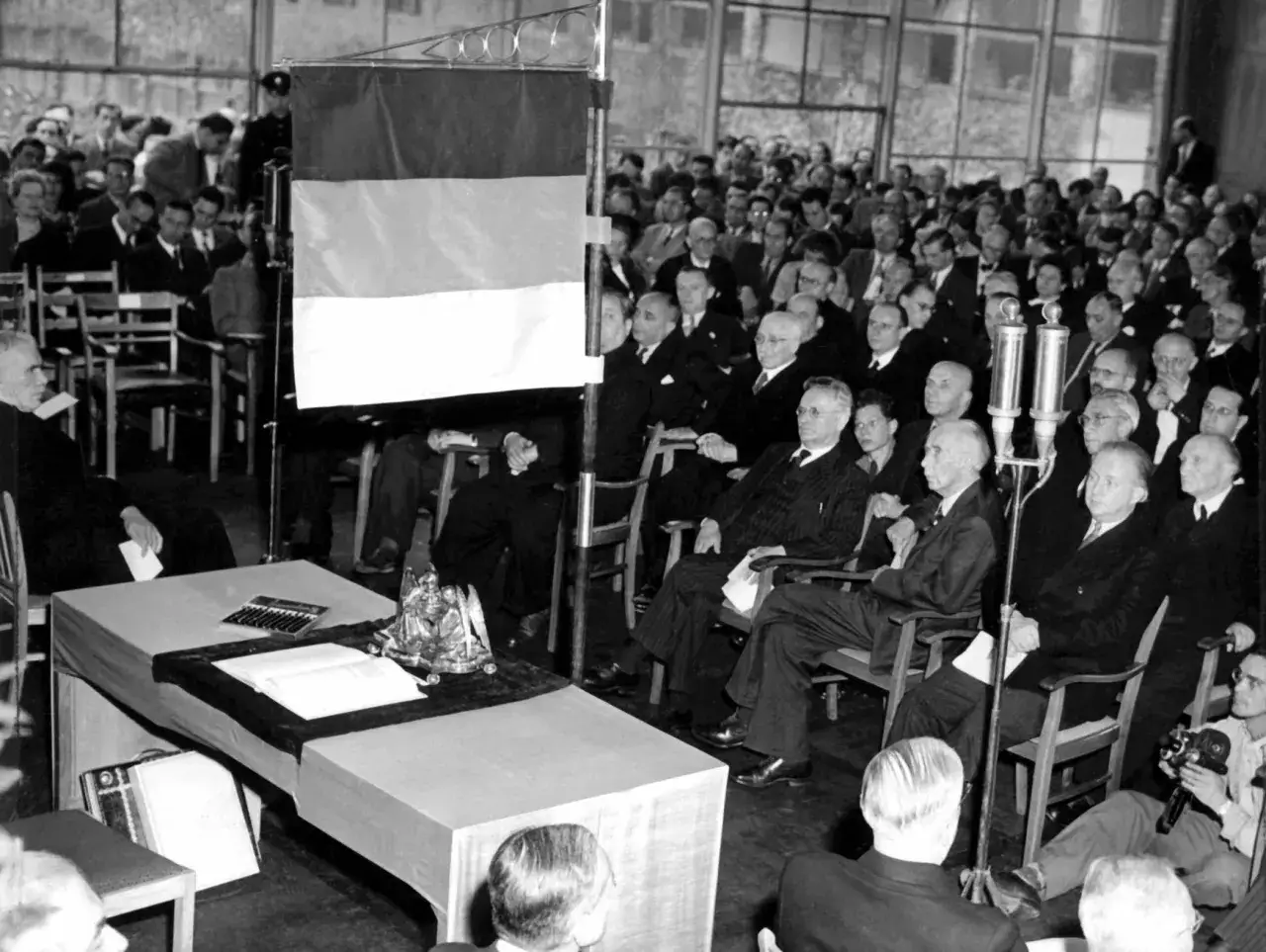 Versammlung im Parlament, als das Grundgesetz geschrieben wurde. Eine deutsche Flagge hängt im Hintergrund.