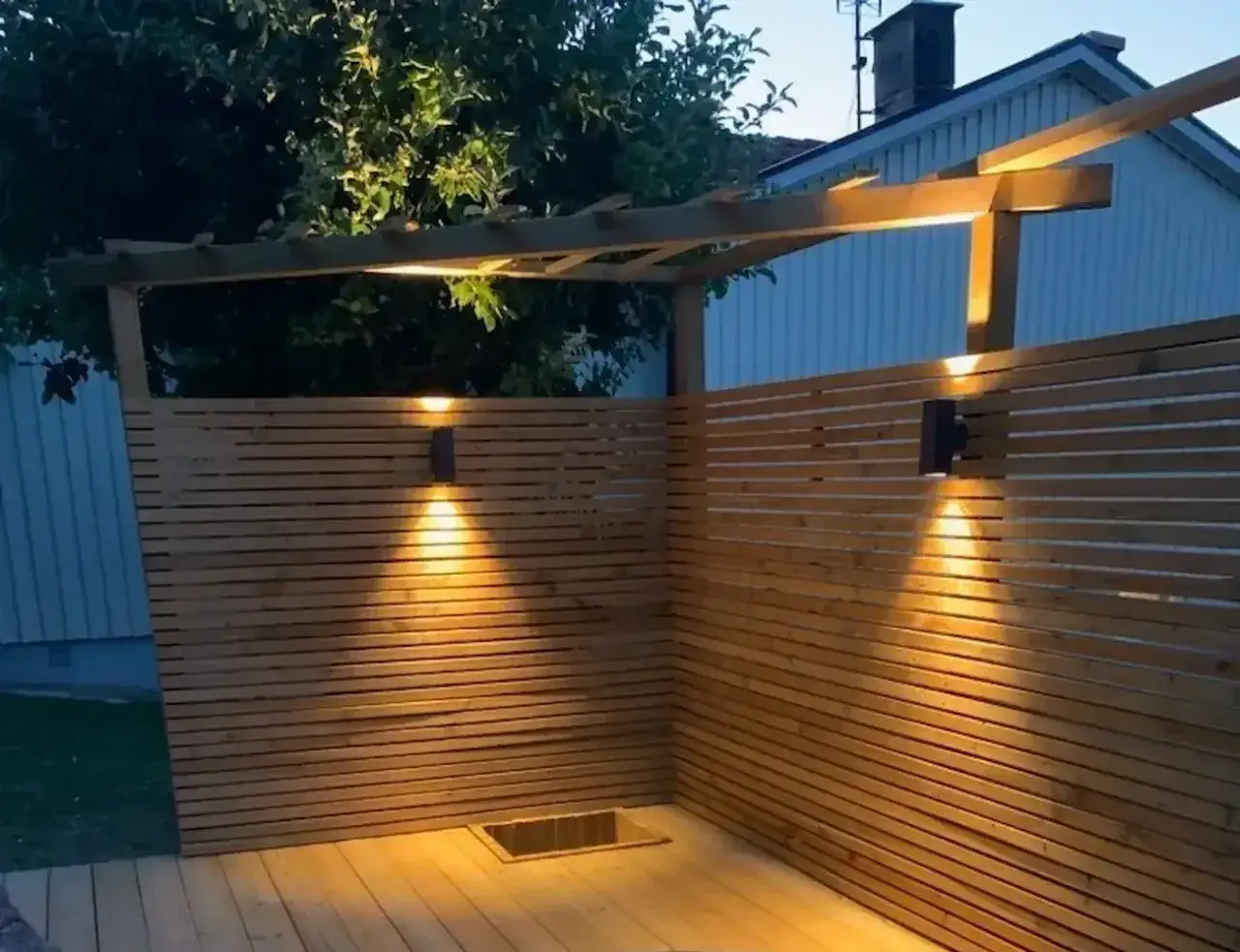 Mysig belysning altan inspiration med tr&auml;panel och pergola. Varma ljusk&auml;glor skapar st&auml;mning.