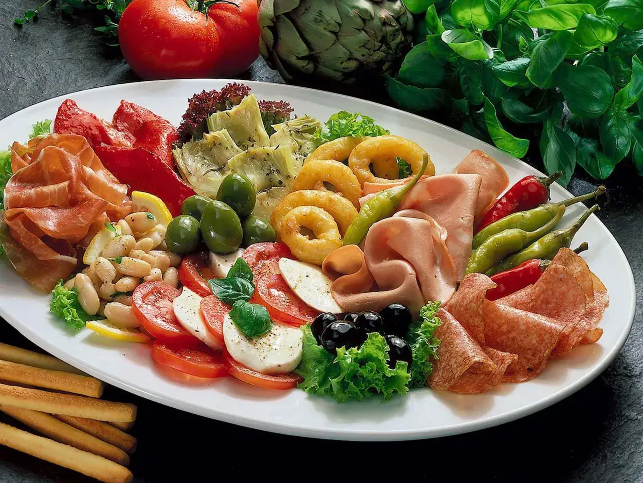 Eine Platte mit geilen Snacks: Schinken, Salami, Mozzarella, Tomaten, Oliven, Artischocken, Bohnen und frittierte Zwiebelringe.