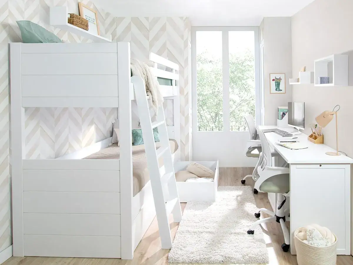 Habitaci&oacute;n estrecha y alargada con literas blancas, escritorio doble y mucha luz natural.