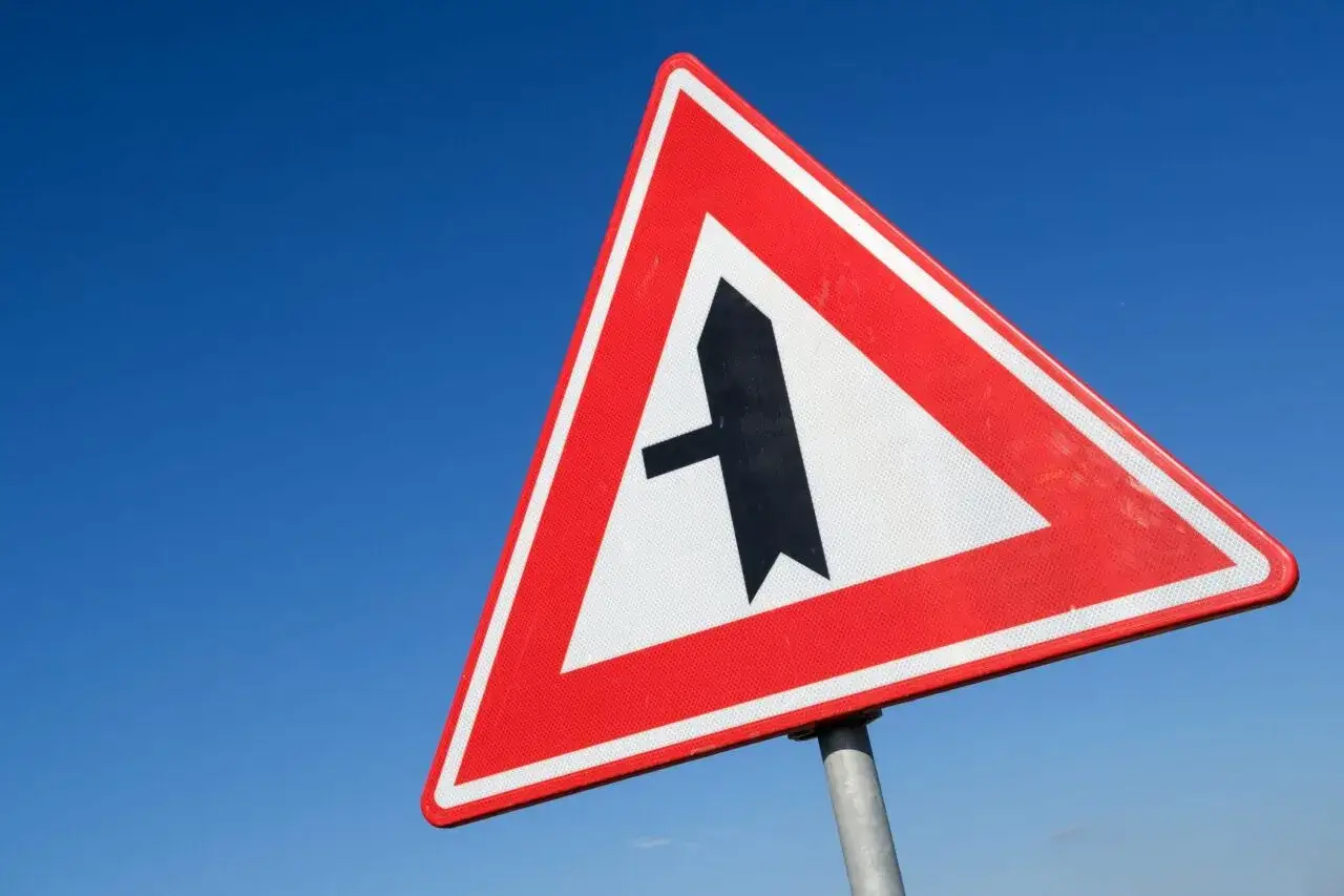 Segnale di pericolo: incrocio con strada secondaria a sinistra. Attenzione alla manovra di svolta.
