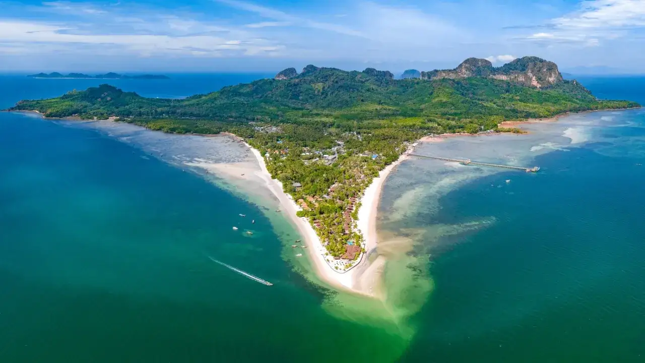 Vacker vy över en V-formad udde med vita sandstränder och turkost vatten. En båt skär genom vattnet vid en **thailand strand**.