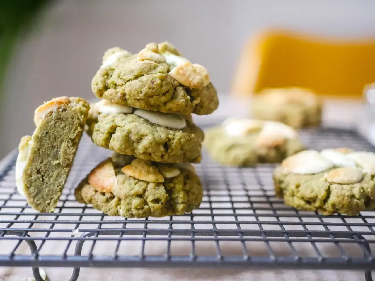 D&eacute;licieux cookies clairs au matcha, empil&eacute;s sur une grille, avec des &eacute;clats de chocolat blanc et des amandes.