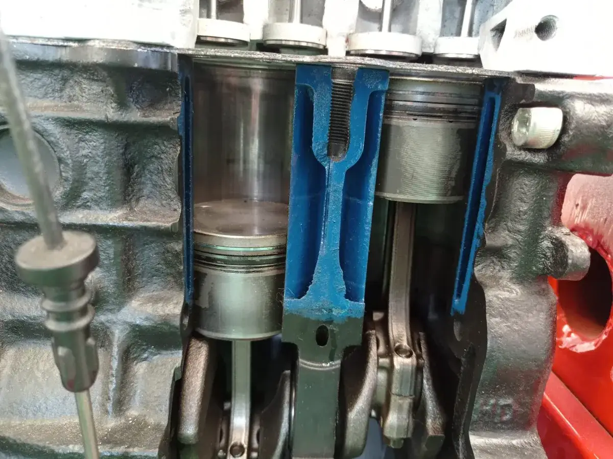 Przekrój silnika z widocznymi tłokami i korbowodami. Widać mechanizm, który generuje **tlok** w cylindrze.