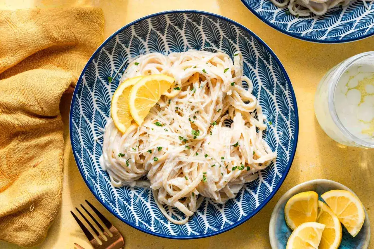En skål med krämig pasta limone, garnerad med citronskivor och färska örter. Enkel men elegant rätt.