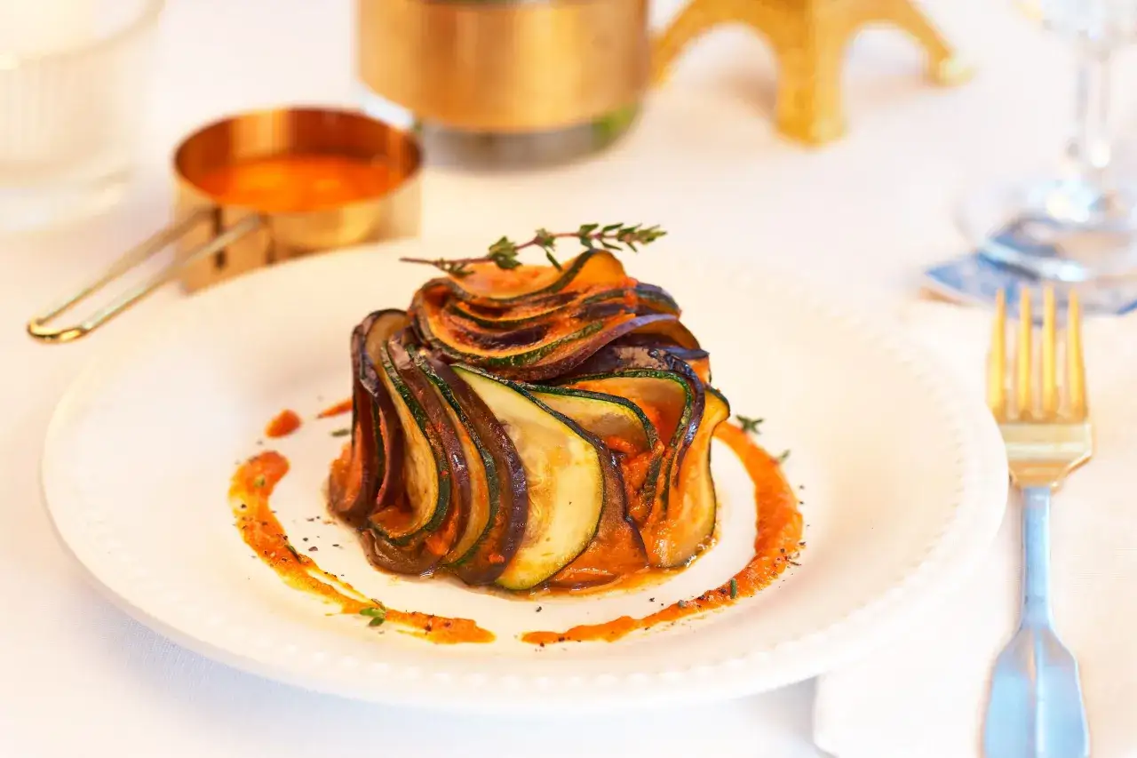 Un plat de ratatouille fa&ccedil;on film, avec des rondelles de l&eacute;gumes (courgette, aubergine) dispos&eacute;es en rosace sur une sauce tomate. Un plat digne d'un chef !