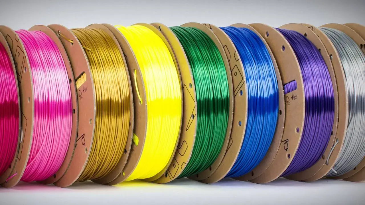 Szpule z kolorowym tworzywem ABS, idealnym do druku 3D. Różne odcienie plastiku, od jaskrawego różu po srebrny, czekają na kreatywne projekty.
