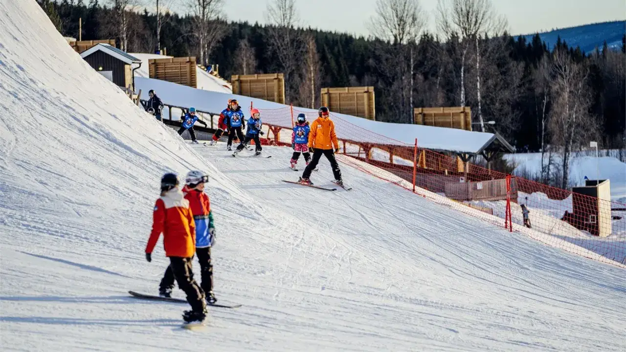 Barn lär sig åka skidor och snowboard i en backe på en av Sveriges mindre skidorter.