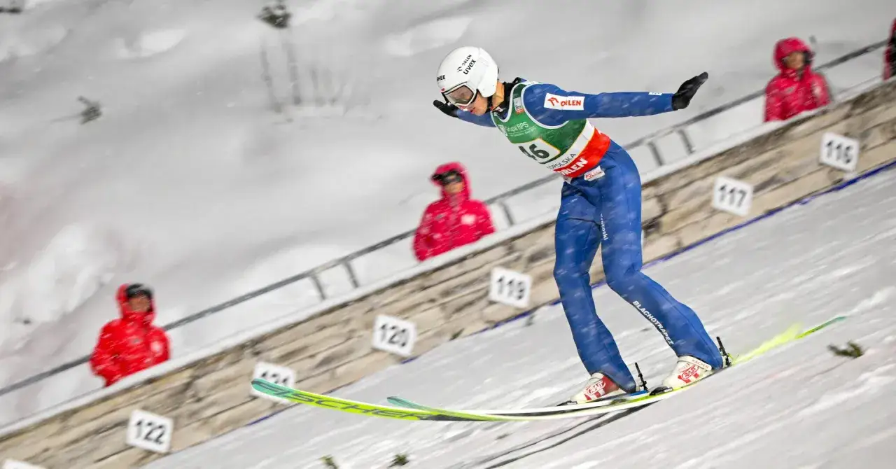 Młody skoczek narciarski w niebieskim kombinezonie szykuje się do skoku. To może być jego start na mistrzostwa świata junior&oacute;w w skokach narciarskich 2026.