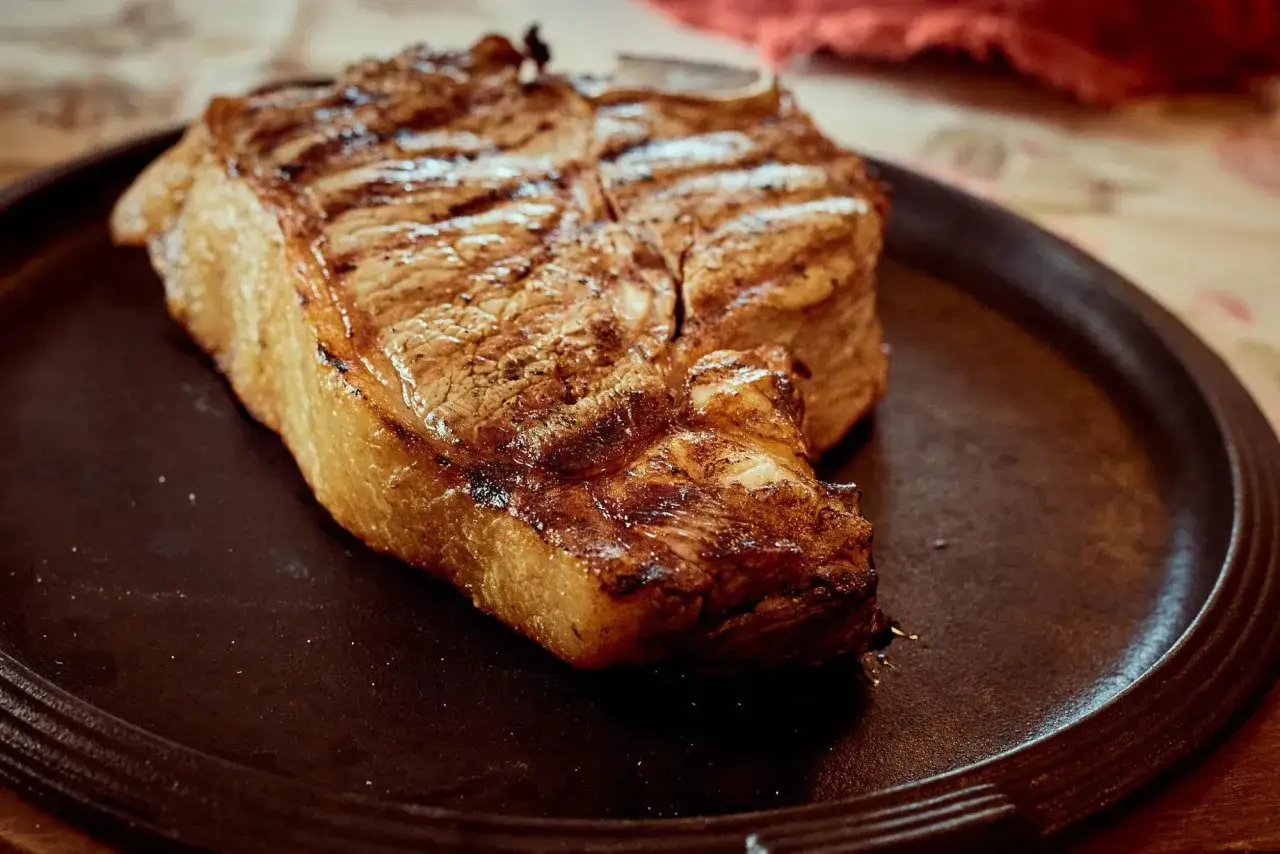 Bistecca alla Fiorentina, un classico delle ricette toscane, servita su un piatto scuro.