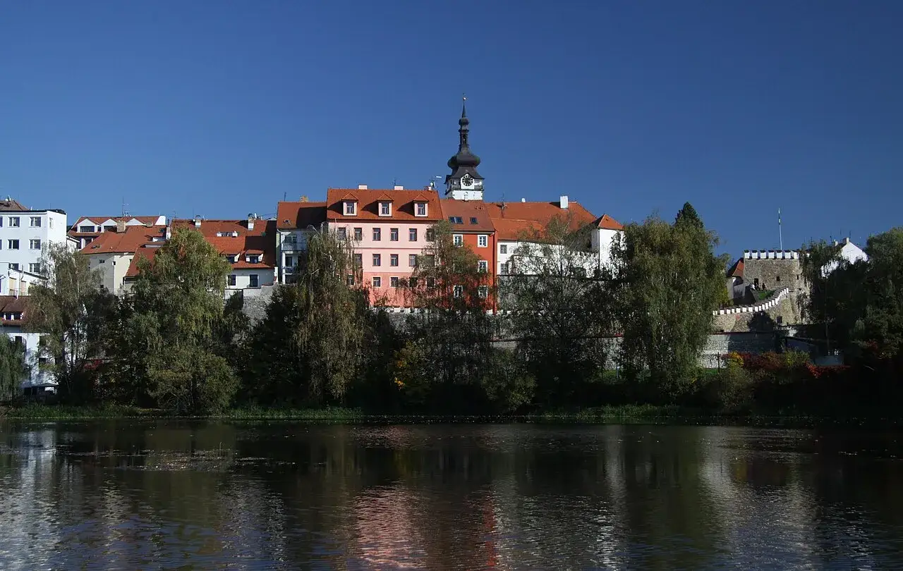 Bunte Häuserfront mit Kirchturm am Flussufer in Písek, Tschechien.