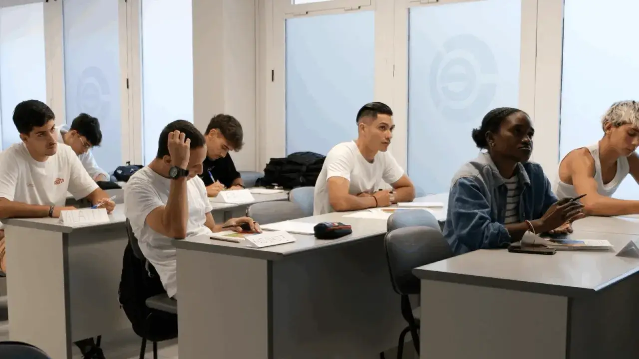 Estudiantes en un aula, participando en una **formaci&oacute;n en centros de trabajo**. Se observan atentos, tomando notas y escuchando.