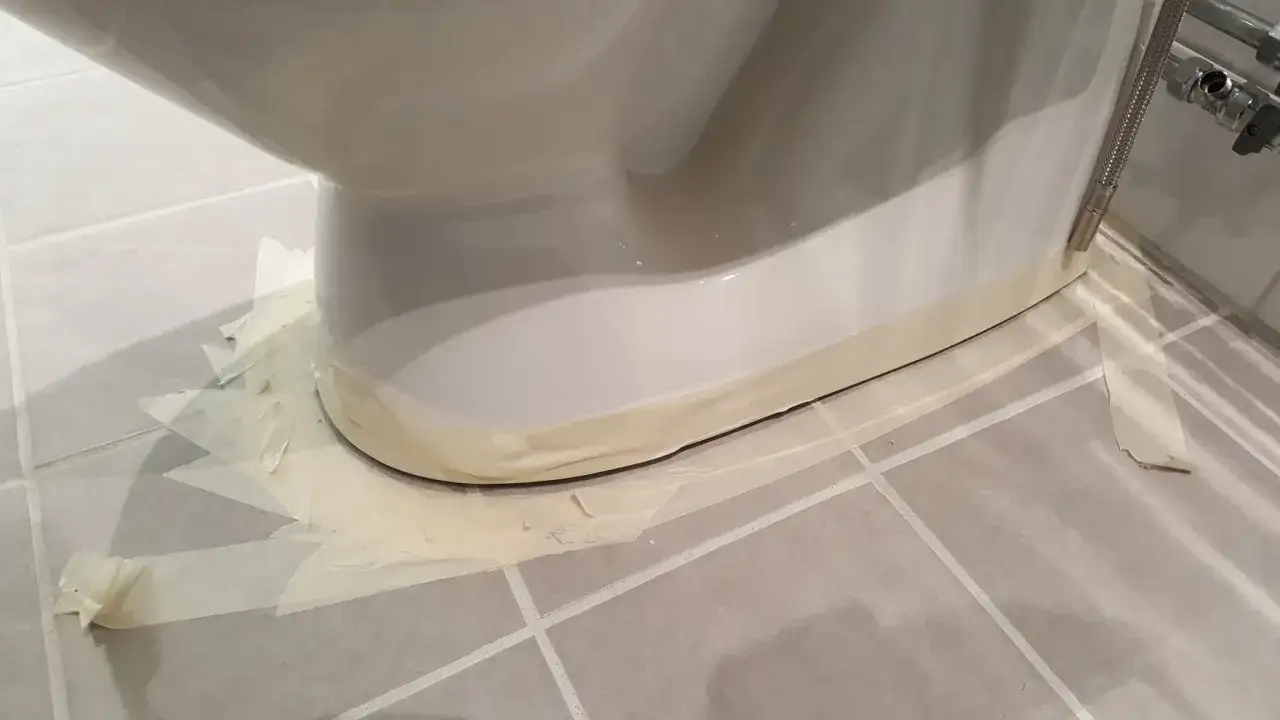 Maskeringstejp runt basen av en toalettstol, redo för fogning.