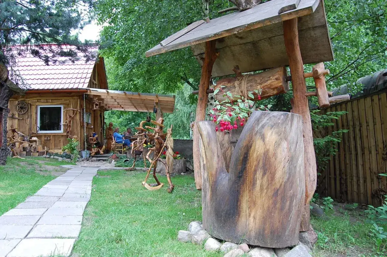 Witaj w krainie rzeźbienia w drewnie! Drewniany domek, studnia i figury tworzą magiczny zakątek.