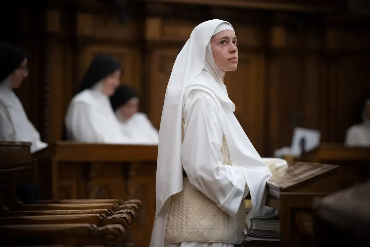A woman in a white habit stands in a monastery, contemplating her path. This image offers a glimpse into the life of a female considering how to join a monastery.