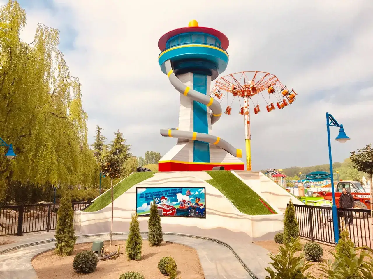 Der Paw Patrol Tower im Nickelodeon Park Deutschland l&auml;dt zu Abenteuern ein. Ein Kettenkarussell dreht sich im Hintergrund.