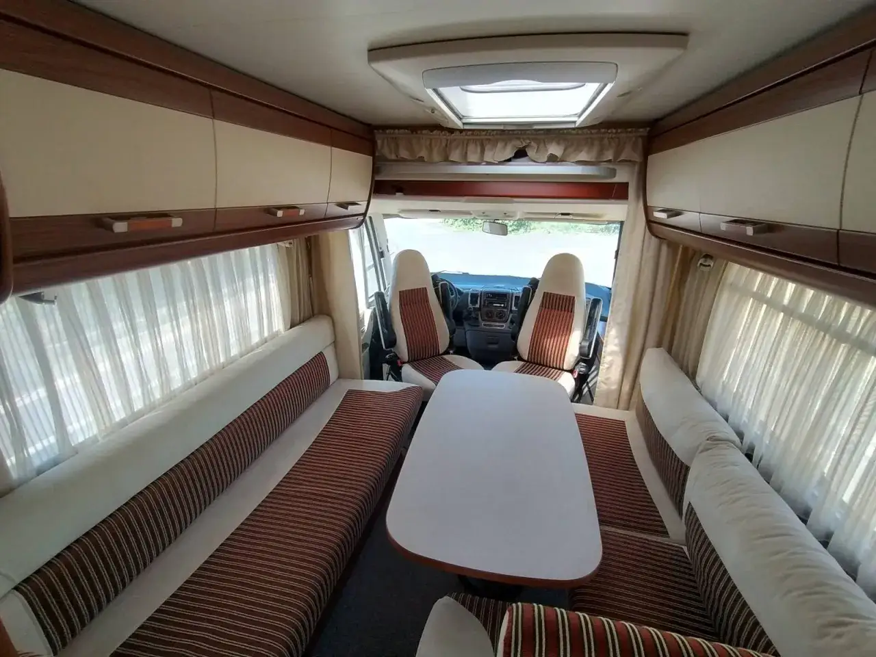 Intérieur d'un camping-car Hymer B544, avec banquettes, table et sièges de cabine. Idéal pour consulter la fiche technique.