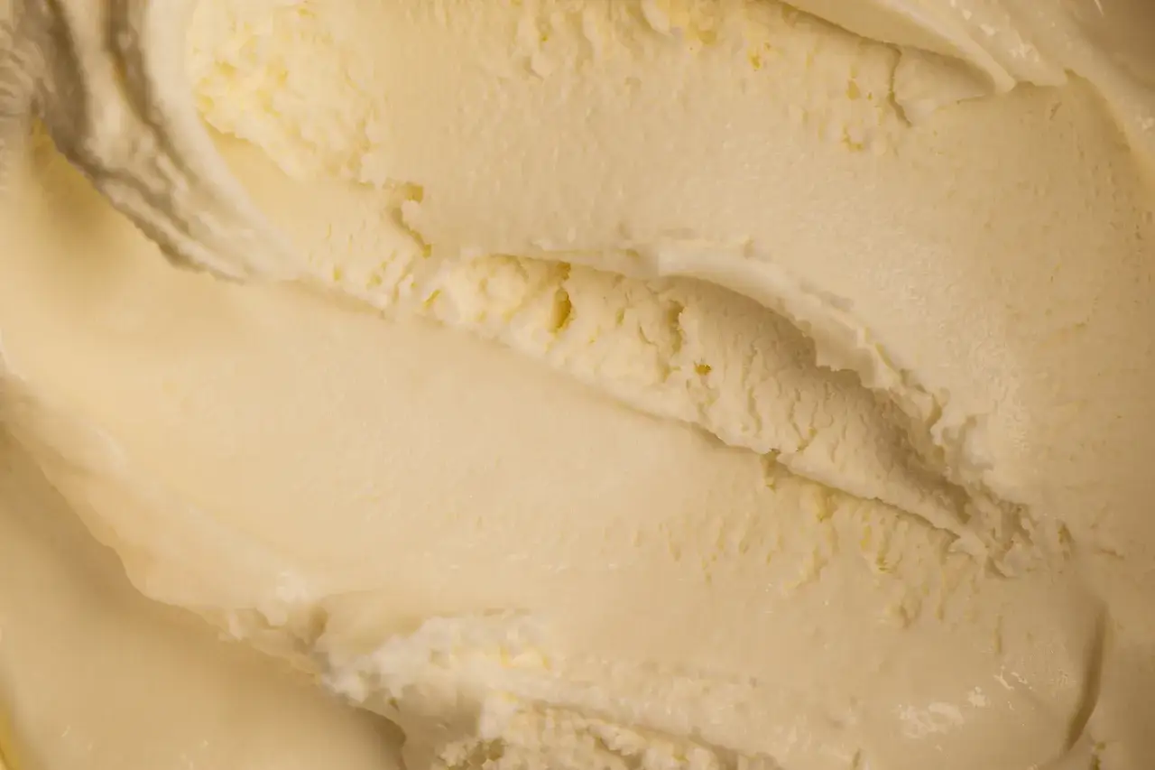 Cremiges, hellgelbes Crème glacée mit sichtbaren Spuren von der Eislöffel-Schöpfung.