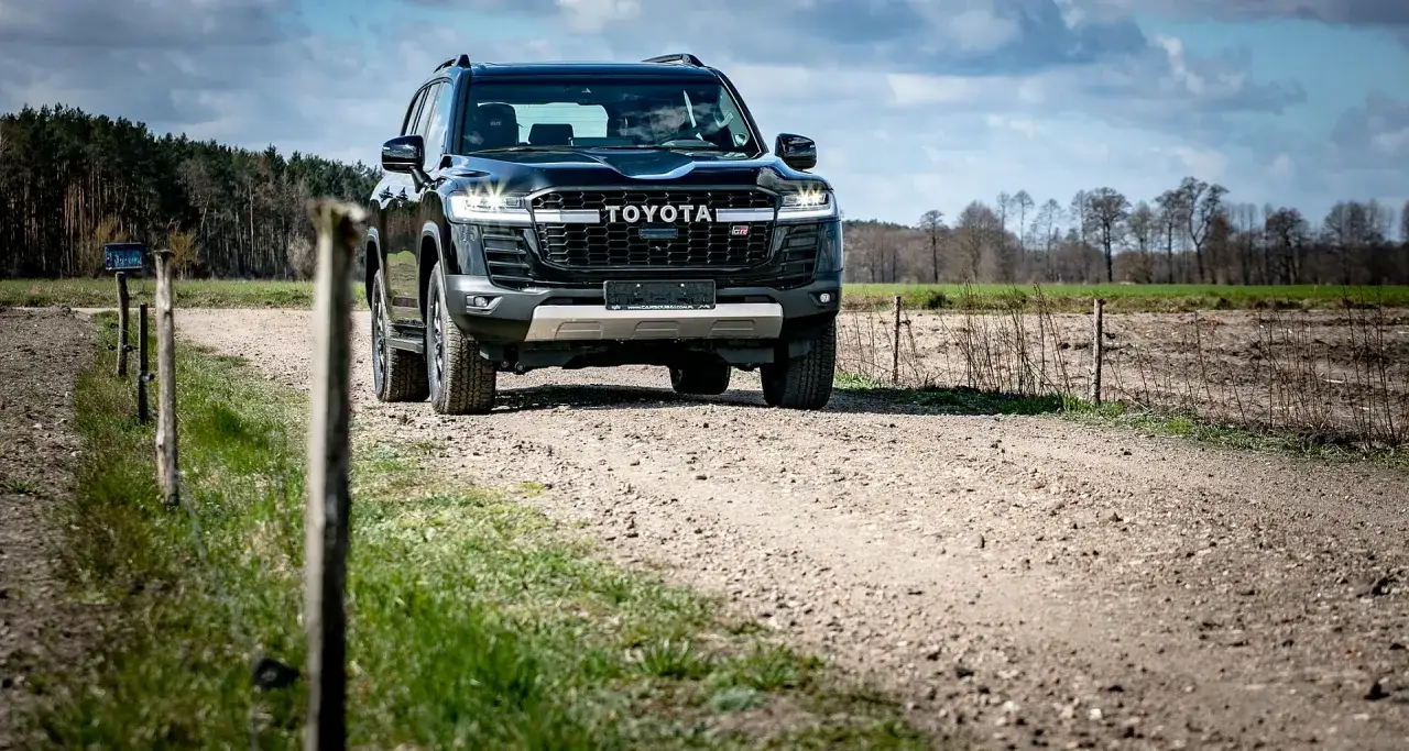 Czarny Toyota Land Cruiser 300 GR Sport na szutrowej drodze, gotowy na przygodę w terenie.