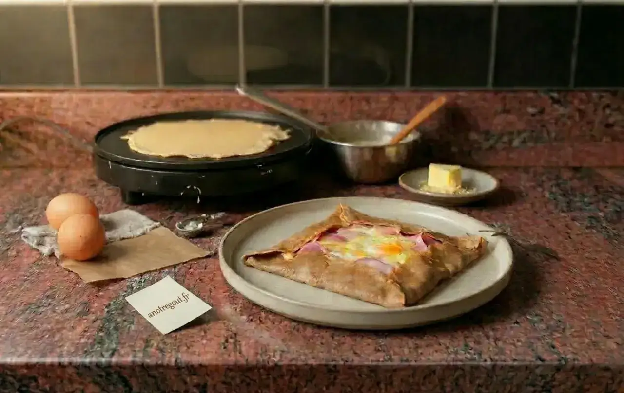 Pr&eacute;paration d'une galette de sarrasin pour 4 personnes : une cr&ecirc;pe cuit sur une cr&ecirc;pi&egrave;re, des &oelig;ufs, du jambon et du fromage dans une galette garnie.