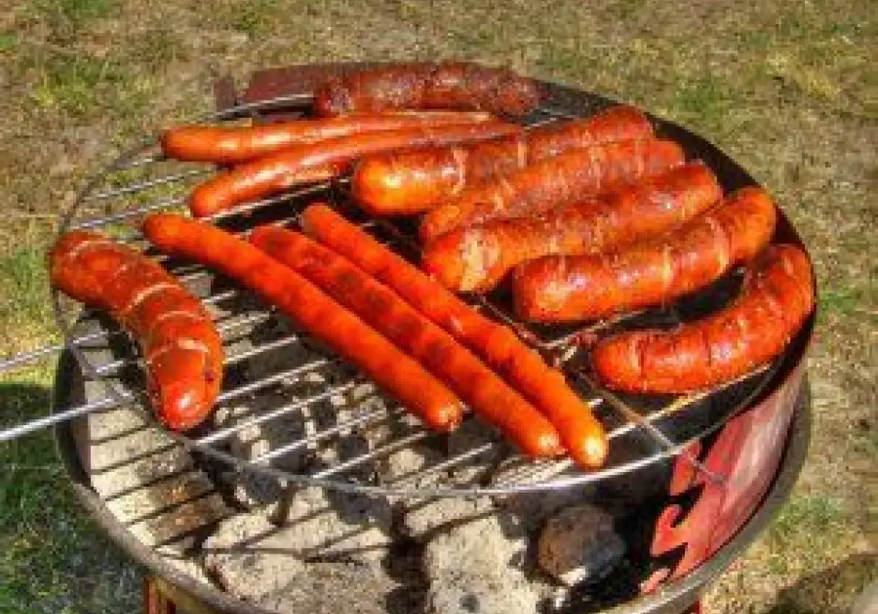 Pyszna kiełbasa na grilla rumieni się na ruszcie, kusząc zapachem. Idealna na letnie popołudnie.
