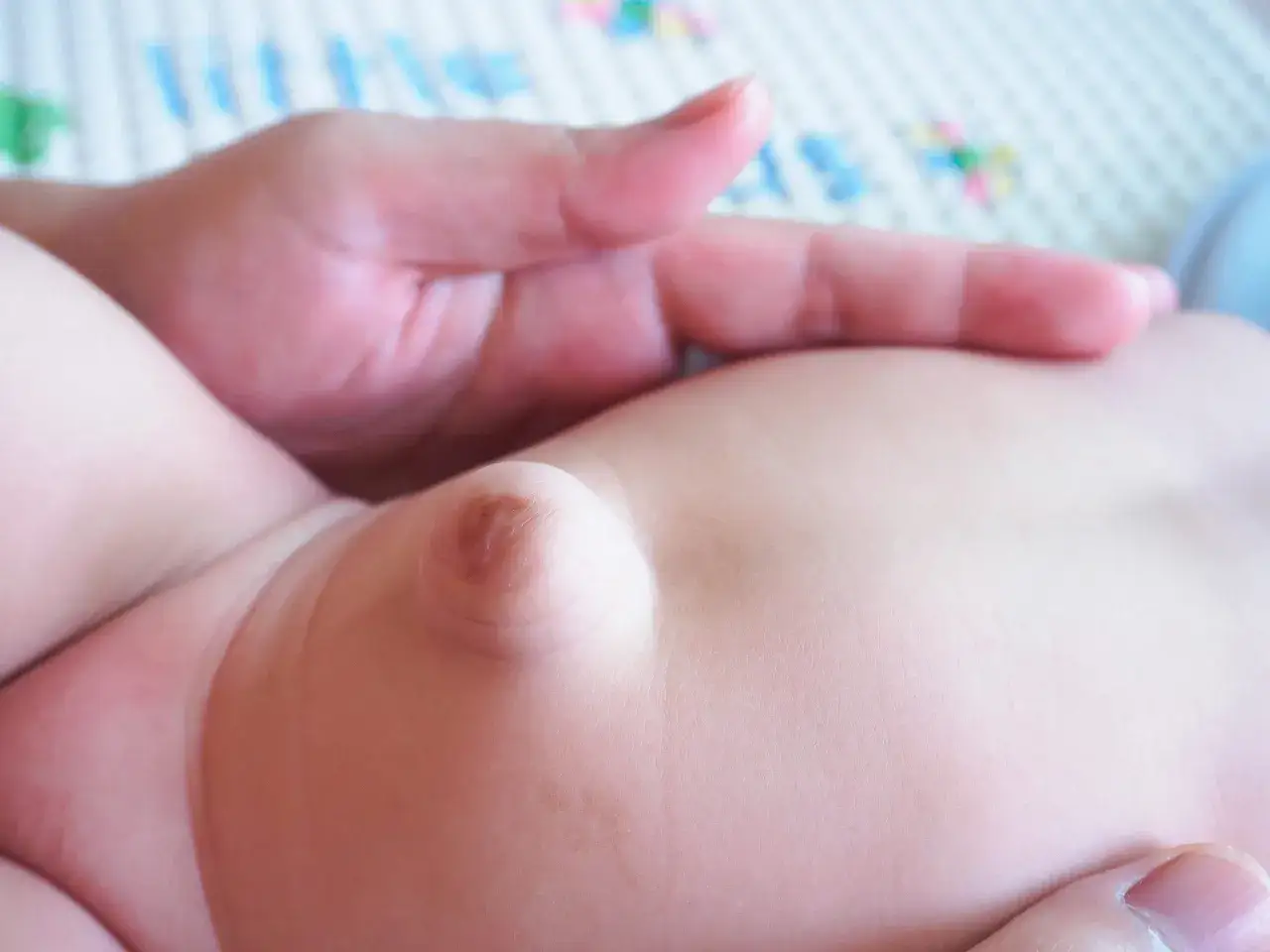 Una mano adulta acaricia la barriguita de un beb&eacute;, mostrando una peque&ntilde;a hernia umbilical.