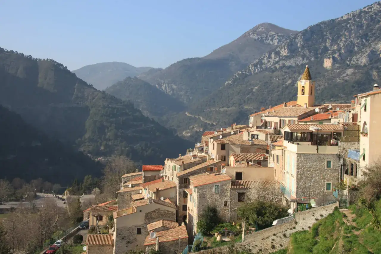 Village perché dans les montagnes, idéal pour savoir où partir en France en mai. Vue sur les toits de tuiles et le clocher.