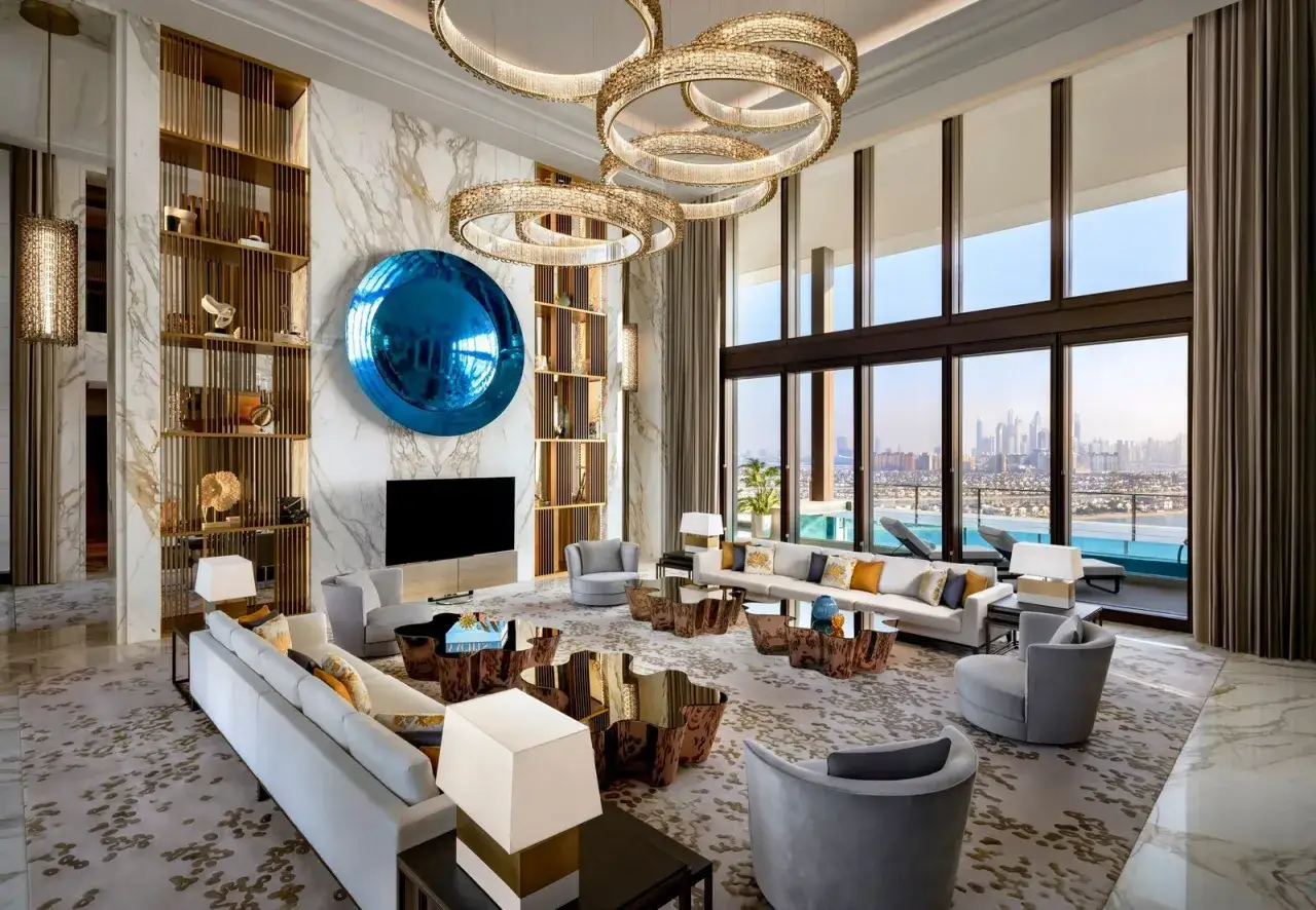 Luksusowy salon z widokiem na miasto, prawdopodobnie najdroższy hotel na świecie. Marmurowe ściany, designerskie meble i ogromne okna.