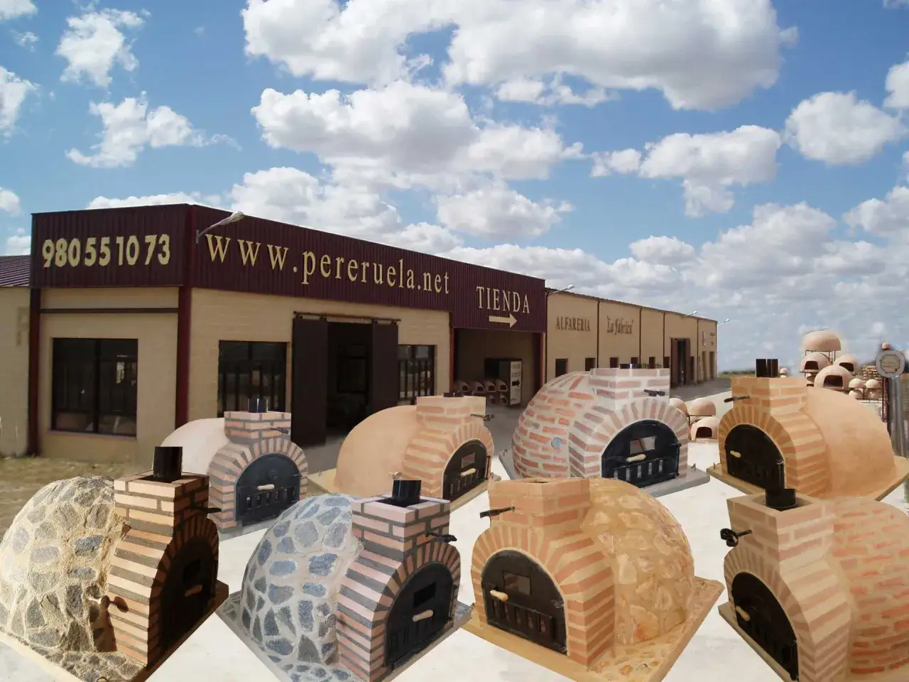 Exhibición de hornos de leña empotrados de diversos materiales y diseños, listos para crear deliciosas pizzas y panes.