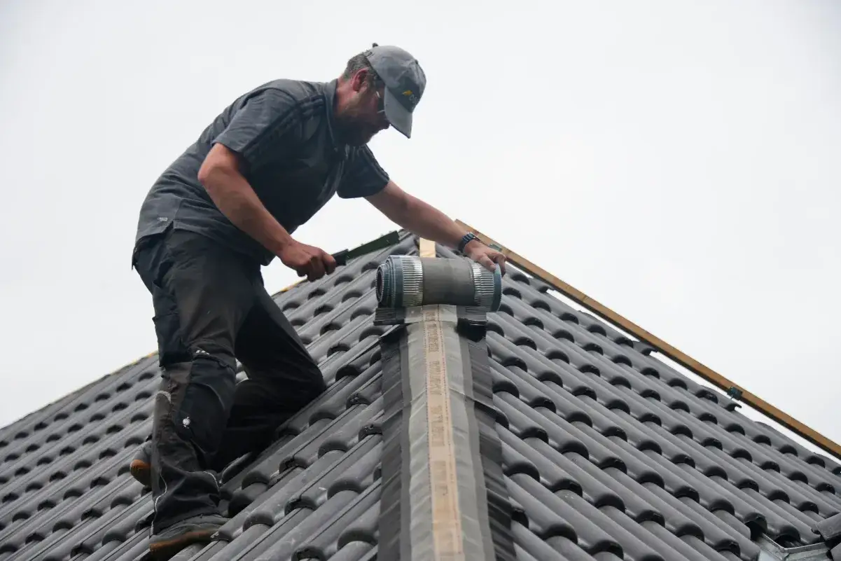 Handwerker auf dem ersten Dach installiert eine Lüftungsrolle.