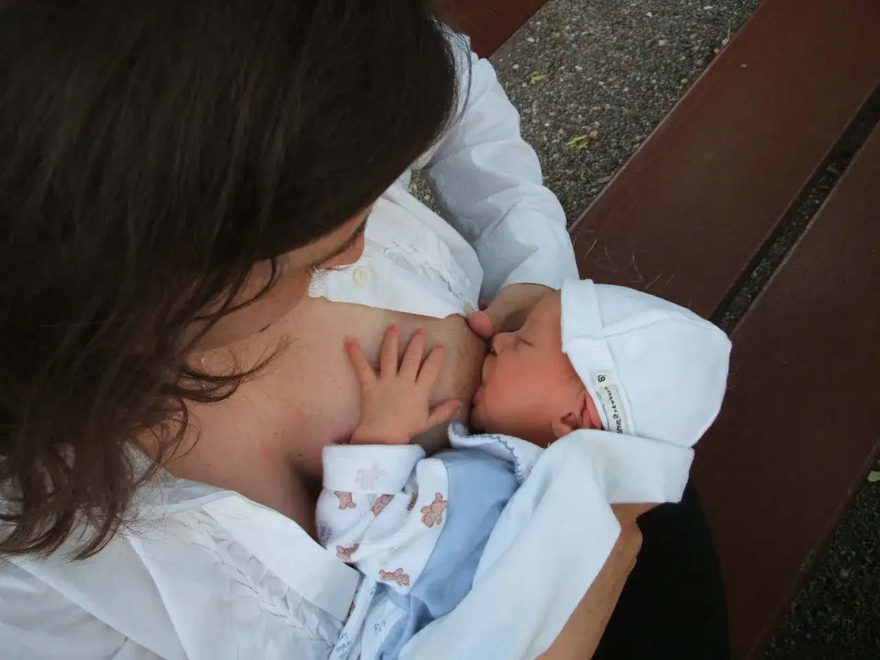 Mamma allatta il suo neonato su una panchina, un momento intimo di allattare in pubblico, serena e naturale.