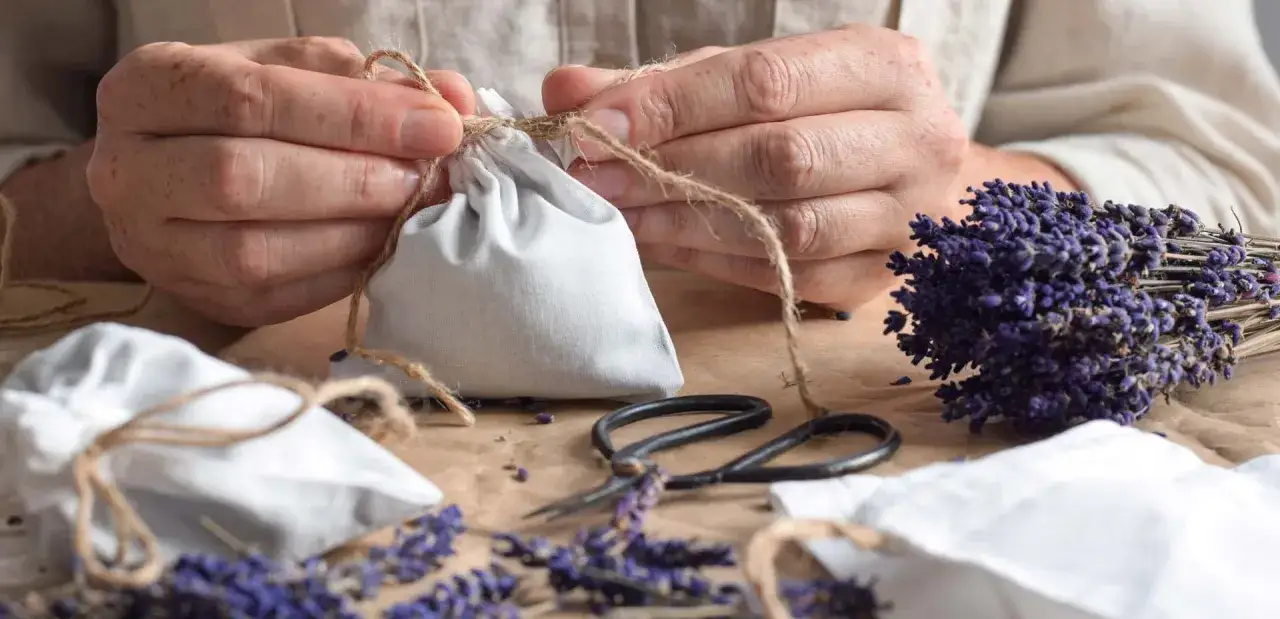 Mani che legano sacchetti anti umidità fai da te con lavanda essiccata e forbici.