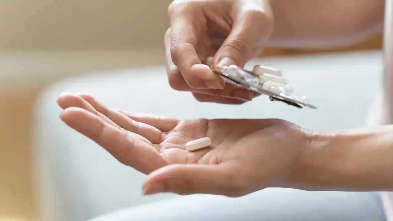 Eine Hand hält eine Tablette, während die andere Hand eine Blisterpackung mit weiteren Pillen hält. Mögliche pregabalin nebenwirkungen im Blick.